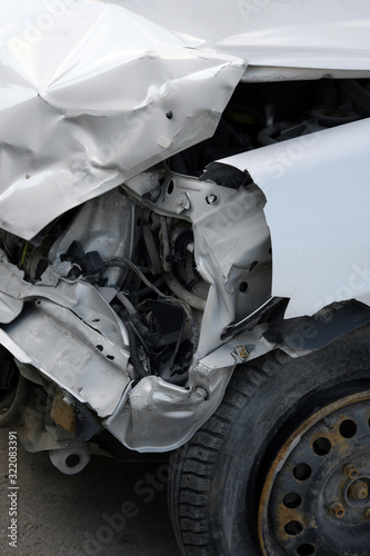 Car crash or accident.Front side of a damaged car. A white car heavily damaged on the front side. Broken vehicle detail or close up. Car insurance concept. 