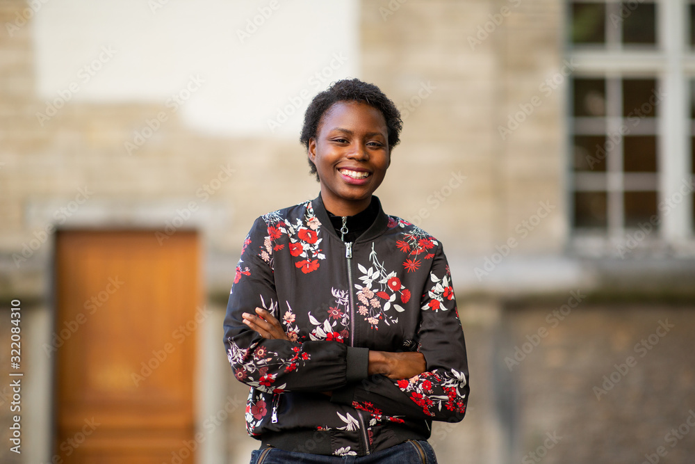 smiling african woman with arms crossed in city looking away smiling african woman with arms crossed in city looking away
