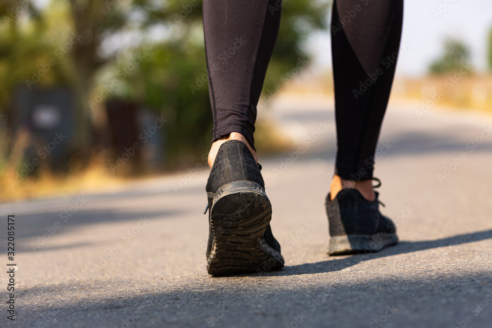 Close up Athlete running woman wearing Exercise pants and running shoe on the road,Runner woman traning in the morning.Walking for warm up her muscle. Close up Athlete running woman wearing Exercise pants and running shoe on the road,Runner woman traning in the morning.Walking for warm up her muscle.