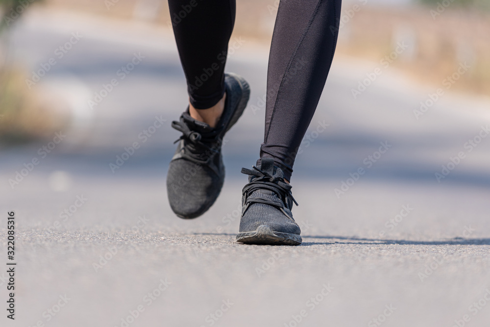 Close up Athlete running woman wearing Exercise pants and running shoe on the road,Runner woman traning in the morning.Walking for warm up her muscle. Close up Athlete running woman wearing Exercise pants and running shoe on the road,Runner woman traning in the morning.Walking for warm up her muscle.