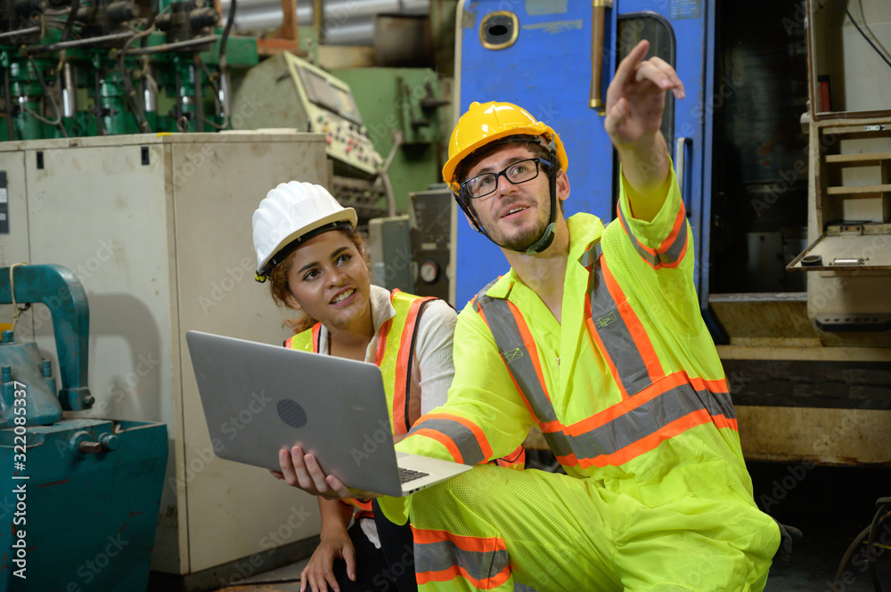 Caucasian male with laptop and mixed race female engineer working in factory area.