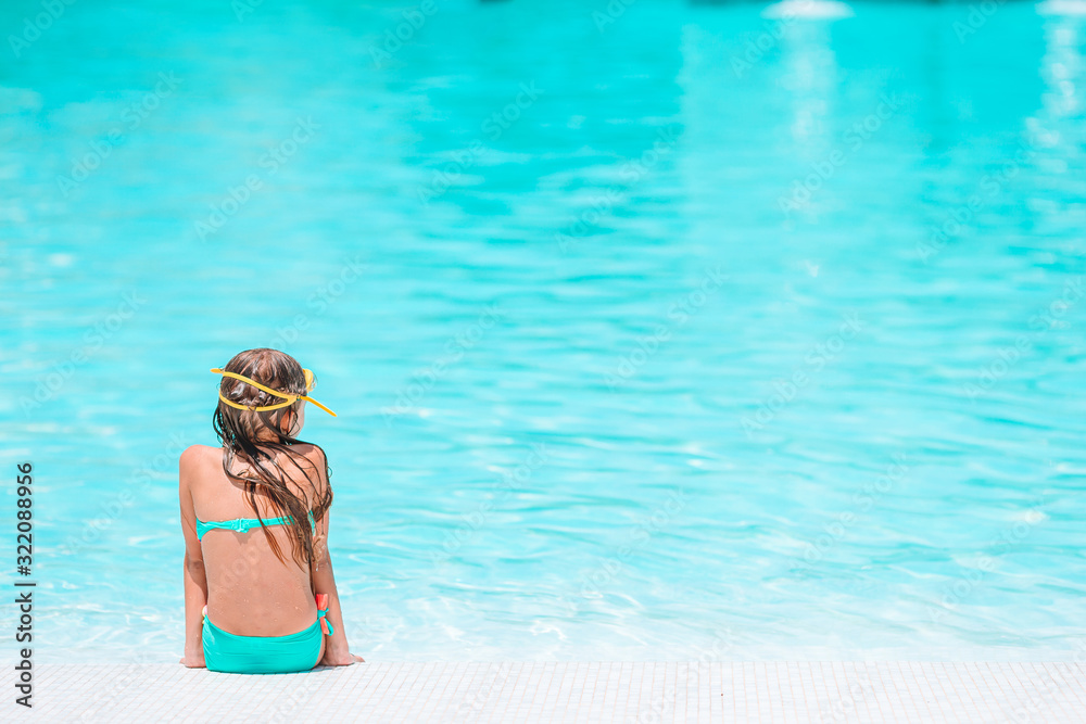 Adorable little girl swimming at outdoor swimming pool