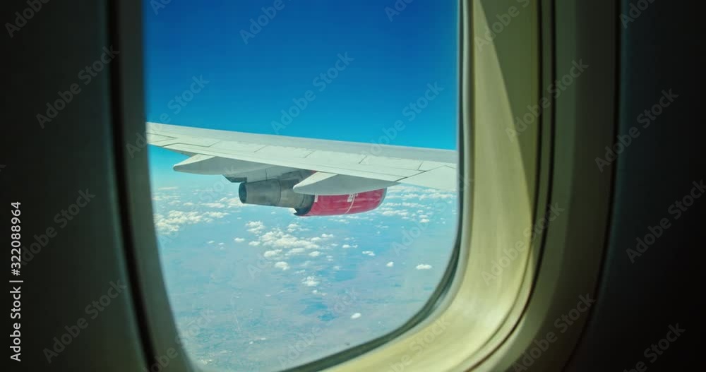 A working jet engine of a flying airplane is visible from the window. A working jet engine of a flying airplane is visible from the window.