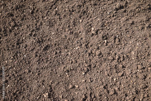 Brown plowed soil on sunlight background