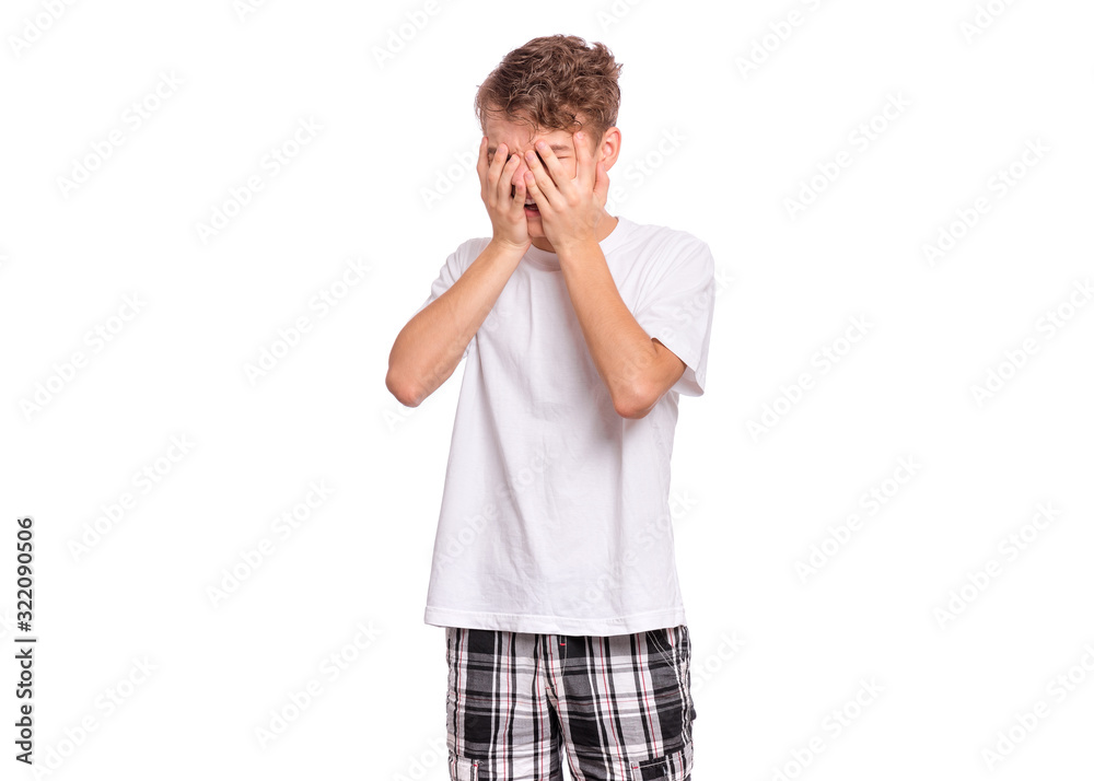 Portrait of young caucasian teen boy covering face with hands while hides tears, isolated on white background. Unhappy teenager is crying. Child in white t-shirt. Portrait of young caucasian teen boy covering face with hands while hides tears, isolated on white background. Unhappy teenager is crying. Child in white t-shirt.