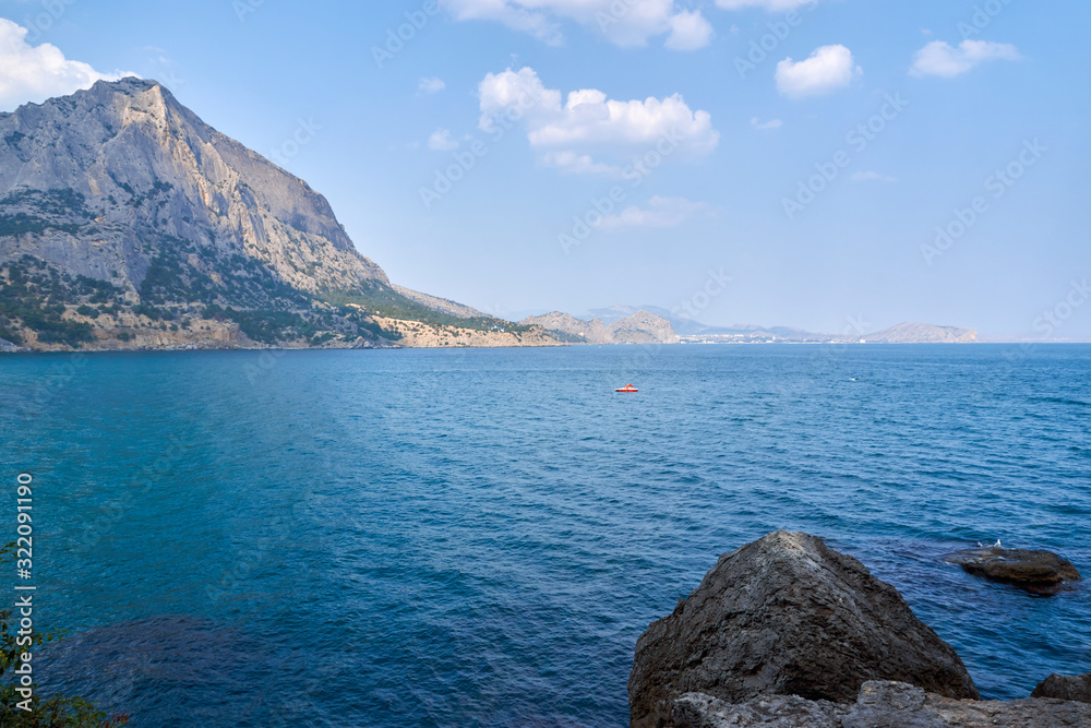 View of the Green Bay in the village of New World, coastal cliffs and a ridge of mountains on the horizon. View of Mount Falcon. Black Sea coast, Sudak region, Republic of Crimea