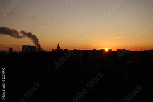 Sunset with a plume of smoke in black and orange in Moscow in winter
