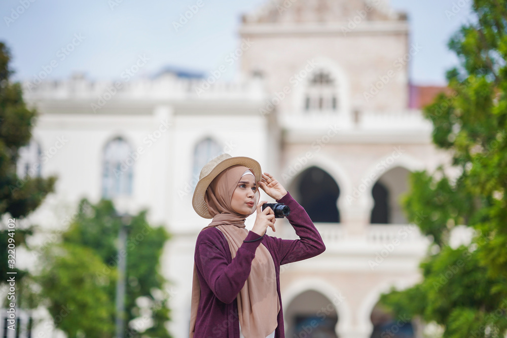 Portrait of beautiful young solo Muslim traveler taking photograph