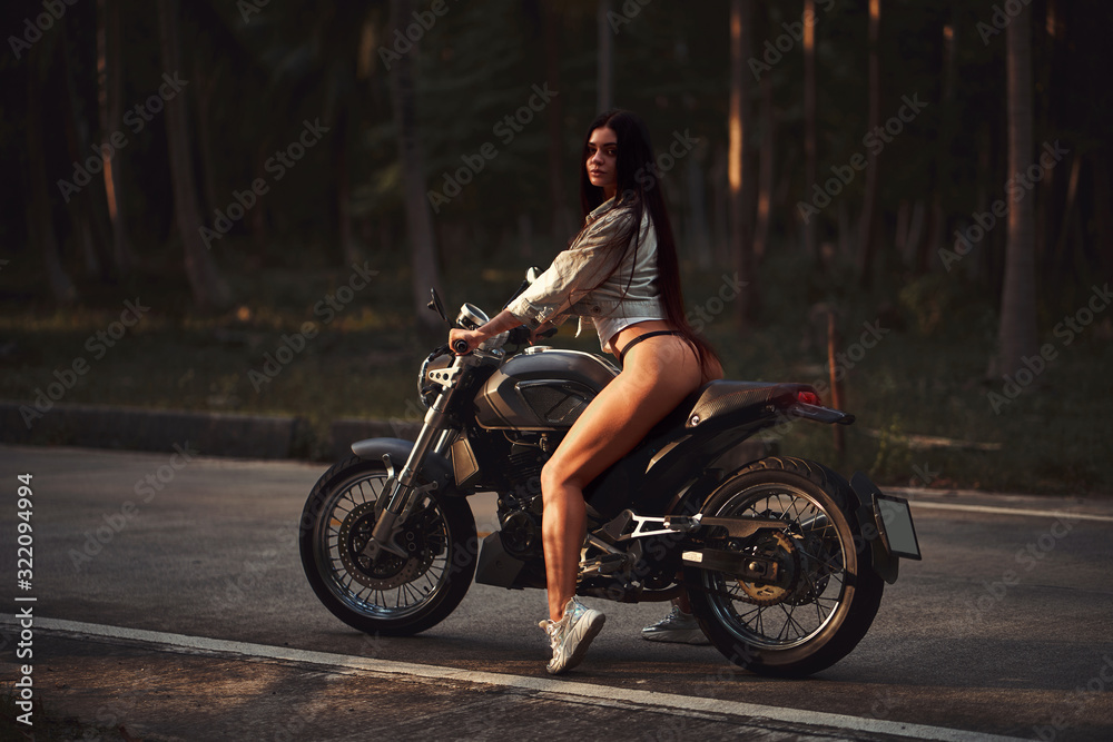 Sexy fit woman with a black motorcycle in cafe racer style