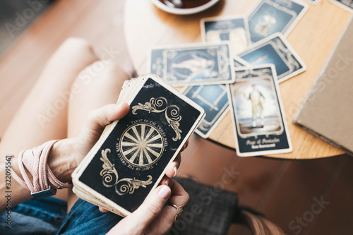 Woman is reading Tarot cards on the table in cafe photo