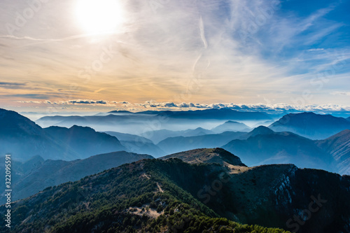 Beautiful captivating landscape of the layered misty hazy French Alps mountain range in Alpes-Maritimes in the afternoon during a sunny day