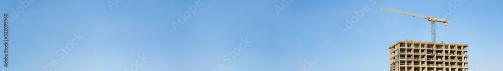 Tower cranes working at construction site against blue sky. Header title construction website. Tower cranes working at construction site against blue sky. Header title construction website.