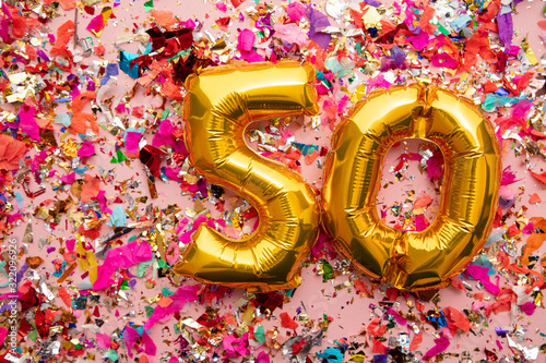 Number 50 gold birthday celebration balloon on a confetti glitter background