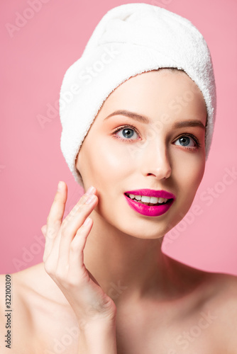 young naked woman in white towel touching face isolated on pink