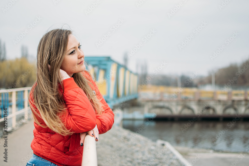 Embrace being single, Art of Being Happily Single. Woman in red jacket walks by the river alone. calm scene