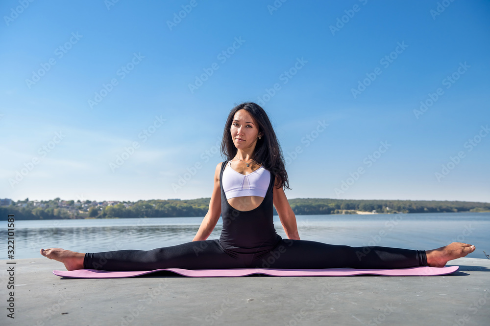 Fototapeta premium Beautiful woman doing split on a warm summer day. sport active lifestyle concept