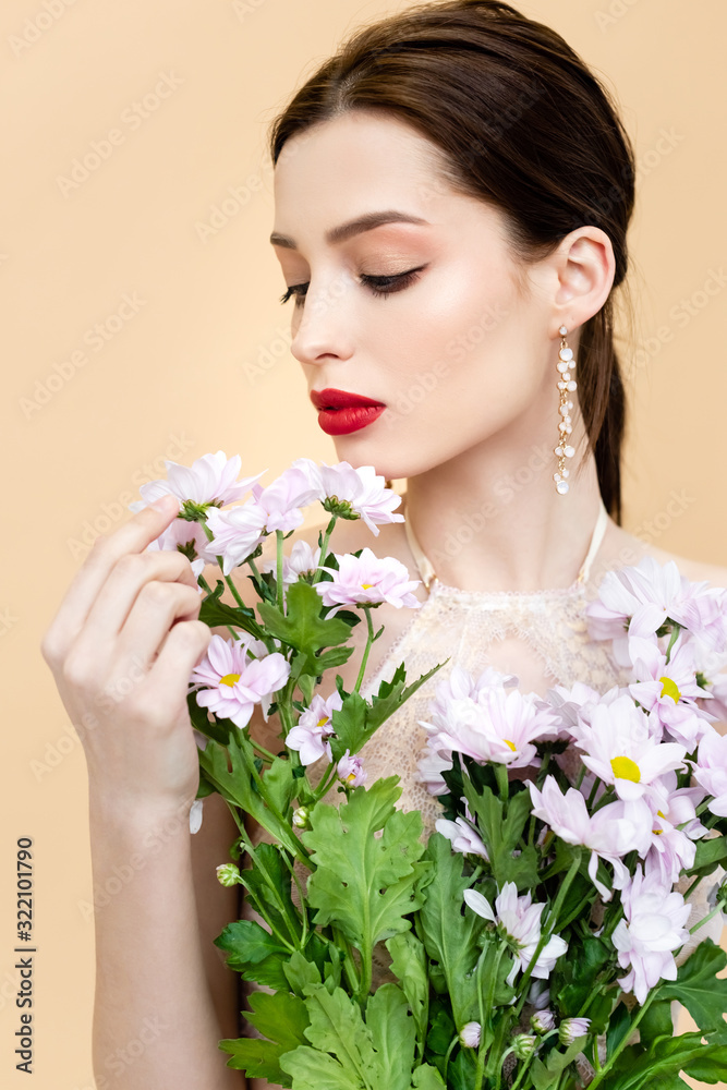 young woman looking at blooming chrysanthemum flowers isolated on beige young woman looking at blooming chrysanthemum flowers isolated on beige