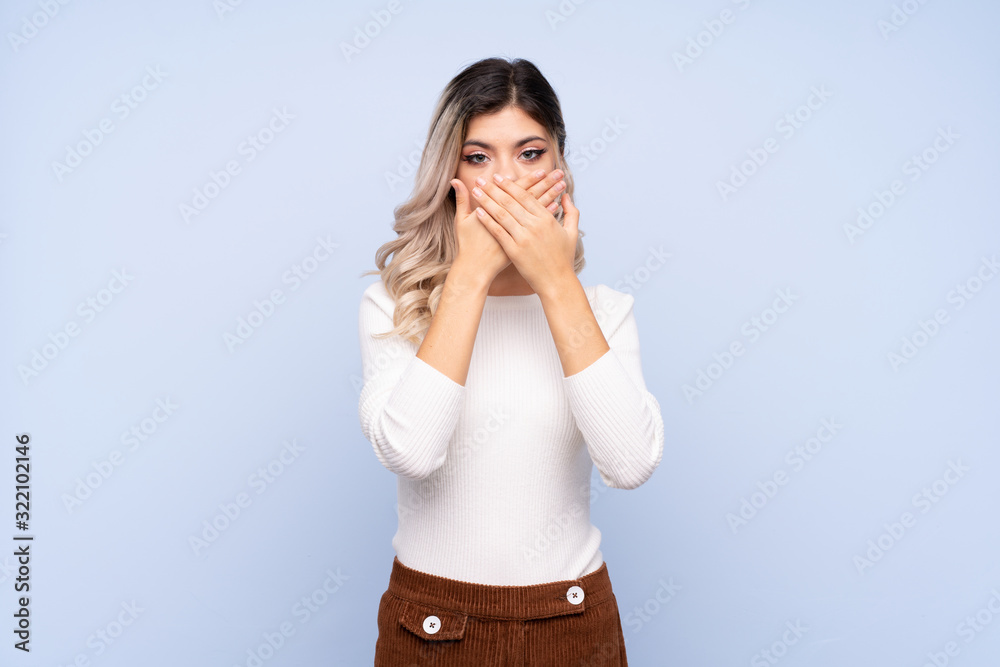 Young teenager girl over isolated blue background covering mouth with hands Young teenager girl over isolated blue background covering mouth with hands