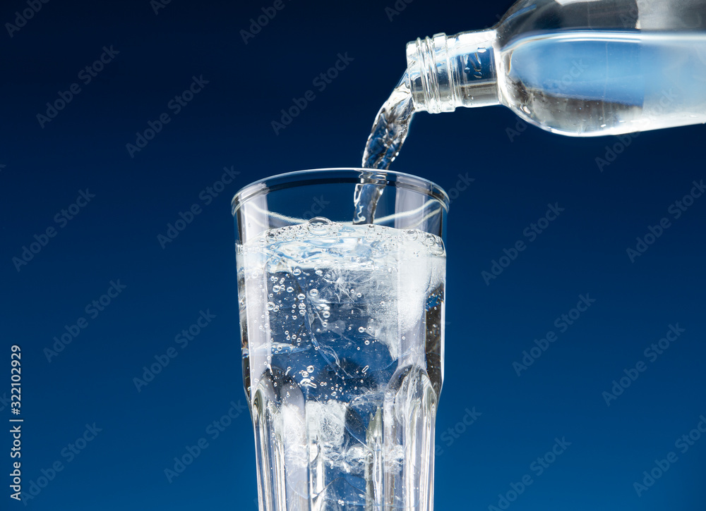 Drinking water pours from a bottle into a glass with ice Drinking water pours from a bottle into a glass with ice