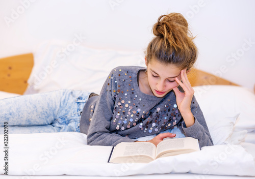 Girl reading a book lying on the bed © trattieritratti