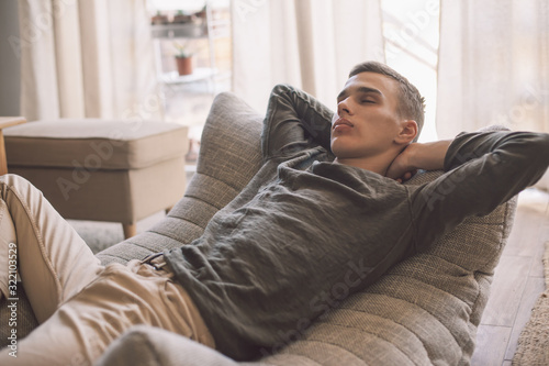 Handsome teenage guy relaxing on modern soft couch at home in living room © Alena Ozerova