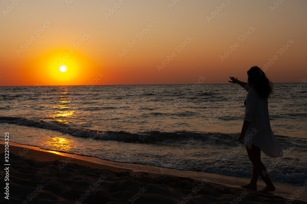 Girl walks along the coast at sunset, sunrise