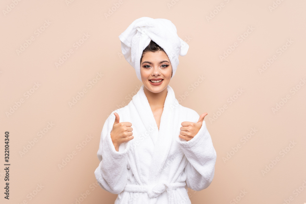 Teenager girl in a bathrobe over isolated background giving a thumbs up gesture Teenager girl in a bathrobe over isolated background giving a thumbs up gesture