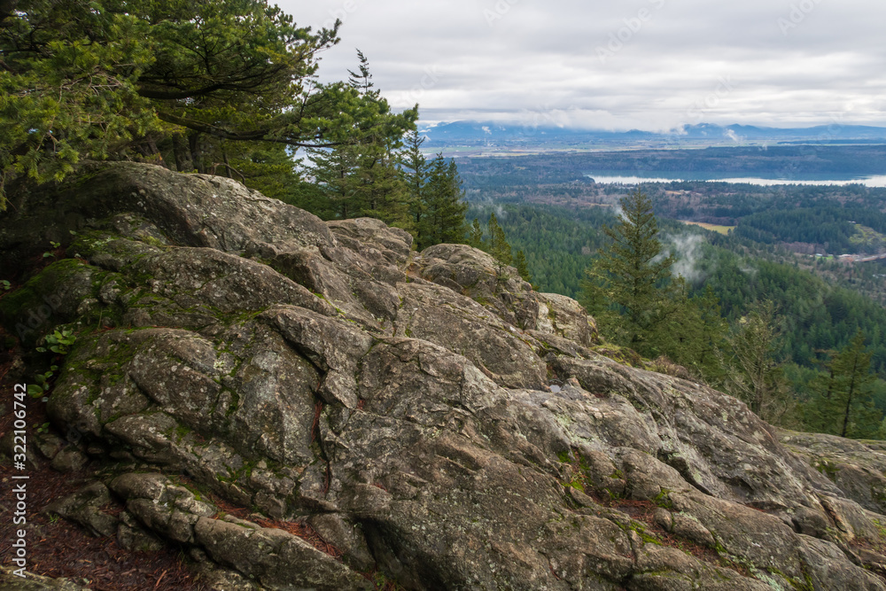 Landscape of large boulder and valley below from Mount Erie in Anacortes, Washington