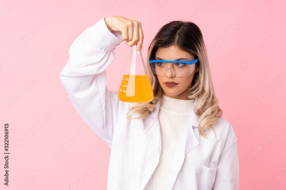 Teenager girl over isolated pink background with a scientific test tube Teenager girl over isolated pink background with a scientific test tube