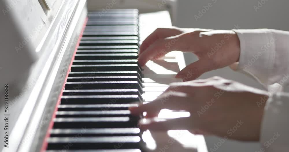 Woman or girl A student or professional pianist plays classical music on a beautiful white piano, hands of a pianist closeup in slow motion. Piano keys close up in dark colors. 4K