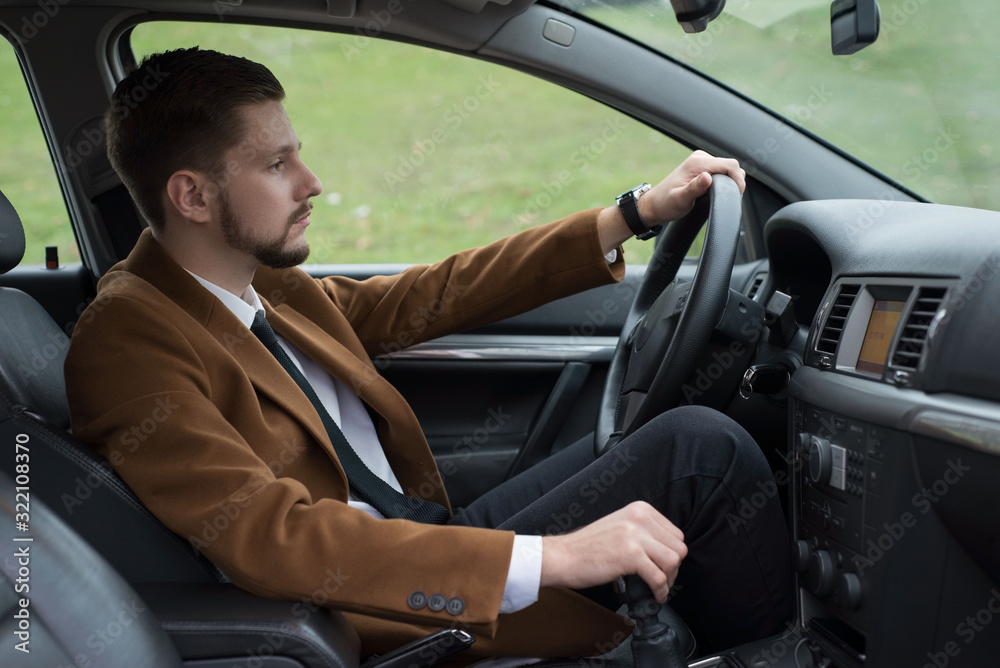 portrait of a young bearded guy in a suit driving a car portrait of a young bearded guy in a suit driving a car