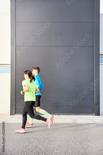 couple of runners running with a modern building in the background