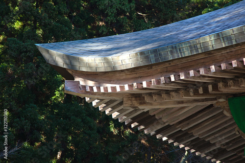 Japanese temple wooden roof corner with dark green trees in the background