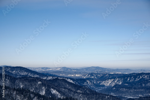 Winter mountain landscape.Snow mountains overgrown with taiga against a blue sky. Russia. Altai Republic.