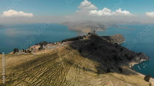 Aerial view of the Island of the Sun (Isla del Sol) in Lake Titicaca in the Andes Mountains at the border between Bolivia and Peru. Hilly dry landscape with small village surrounded by deep blue water photo