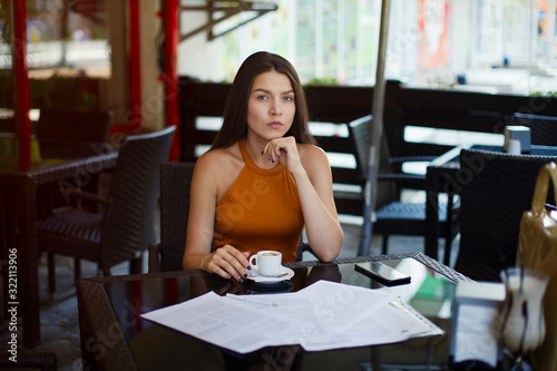 business woman sitting over a cup of tea in a cafe. Signature of important documents. Business meeting. © tumskaia