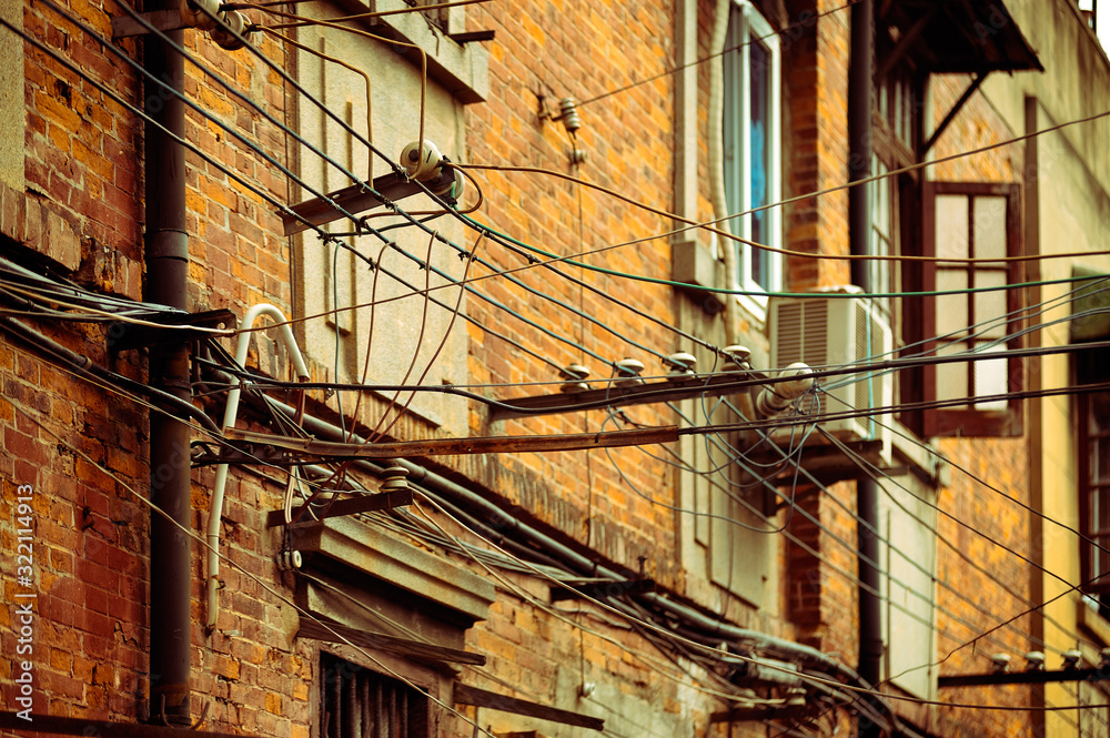 Outdated electrical network, old wires fixed to brick building facade. Shanghai, China.