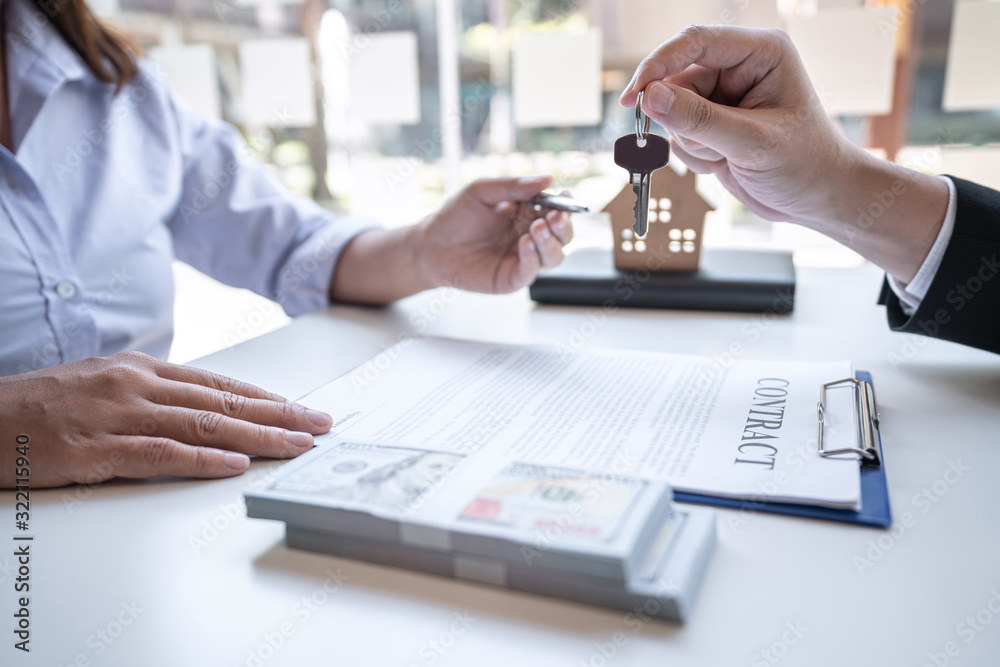 Real estate agent are presenting home loan and giving house, keys to customer after signing contract to buy house with approved property application form Real estate agent are presenting home loan and giving house, keys to customer after signing contract to buy house with approved property application form