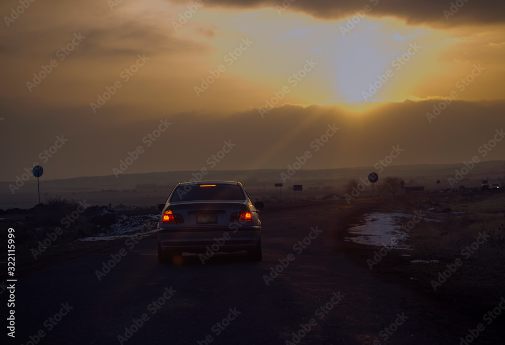 Road traffic in the sunset. Car on asphalt under a cloudy sky.