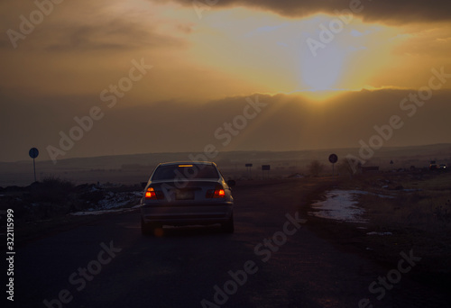 Road traffic in the sunset. Car on asphalt under a cloudy sky.