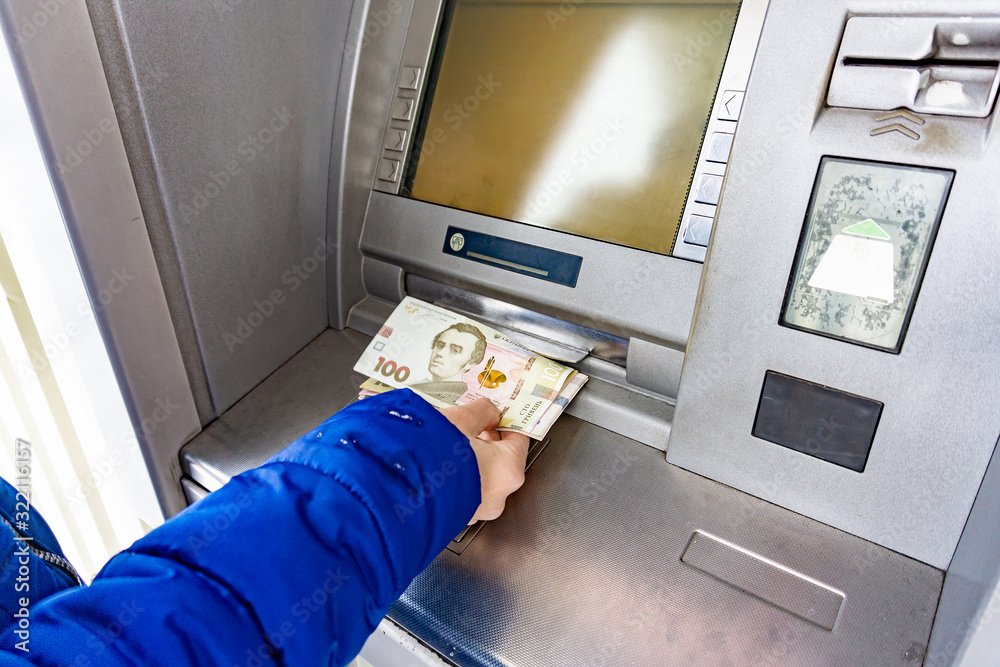 A woman at an ATM withdraws cash hryvnias in Ukraine, 100 and 500 hryvnia notes. A woman at an ATM withdraws cash hryvnias in Ukraine, 100 and 500 hryvnia notes.