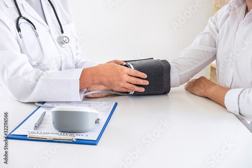 Doctor using Blood pressure monitor and stethoscope checking measuring arterial blood pressure on arm to a patient in the hospital  healthcare and medical concept