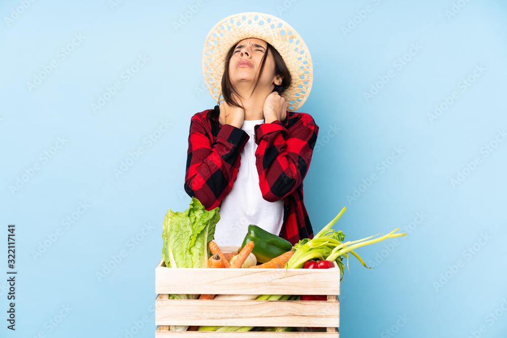 Young farmer Woman holding fresh vegetables in a wooden basket with neckache
