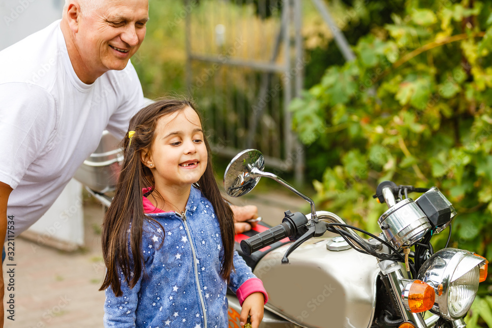 Obraz premium happy grandfather and his granddaughter near bike smiling