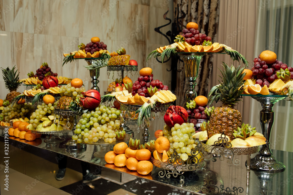 Different fresh fruits on wedding buffet table. Wedding reception catering table with different fruits. Catering table with different kind of fruits. Various sweet sliced fruit on a buffet table. Wedd