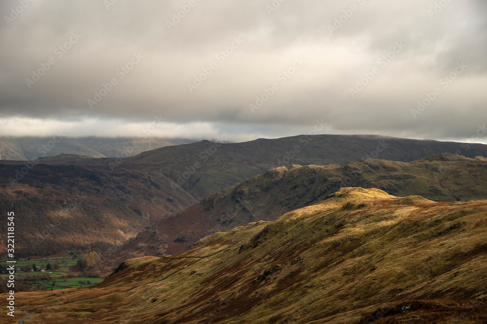 Stunning Autumn Fall landscape of Lake District hills and countryisde with sunlight hitting hillside