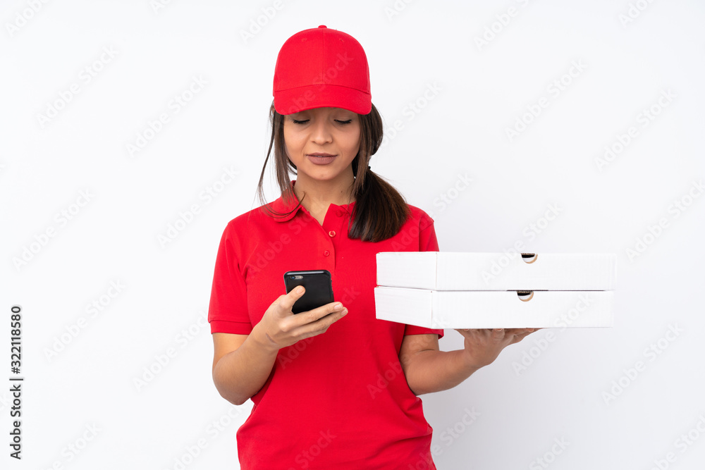 Young Pizza delivery girl over isolated white background sending a message with the mobile Young Pizza delivery girl over isolated white background sending a message with the mobile