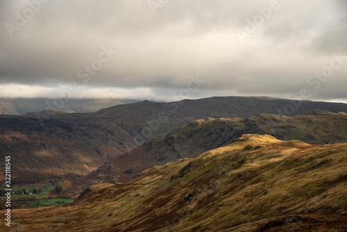 Stunning Autumn Fall landscape of Lake District hills and countryisde with sunlight hitting hillside