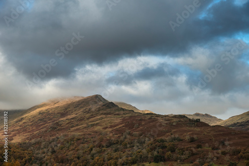 Beautiful Autumn Fall landscape view of mountains in beautiful golden sunlight against dramatic sky