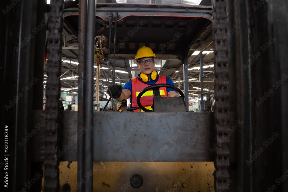 Asian forklift driver at workplace in factory and looking at the camera